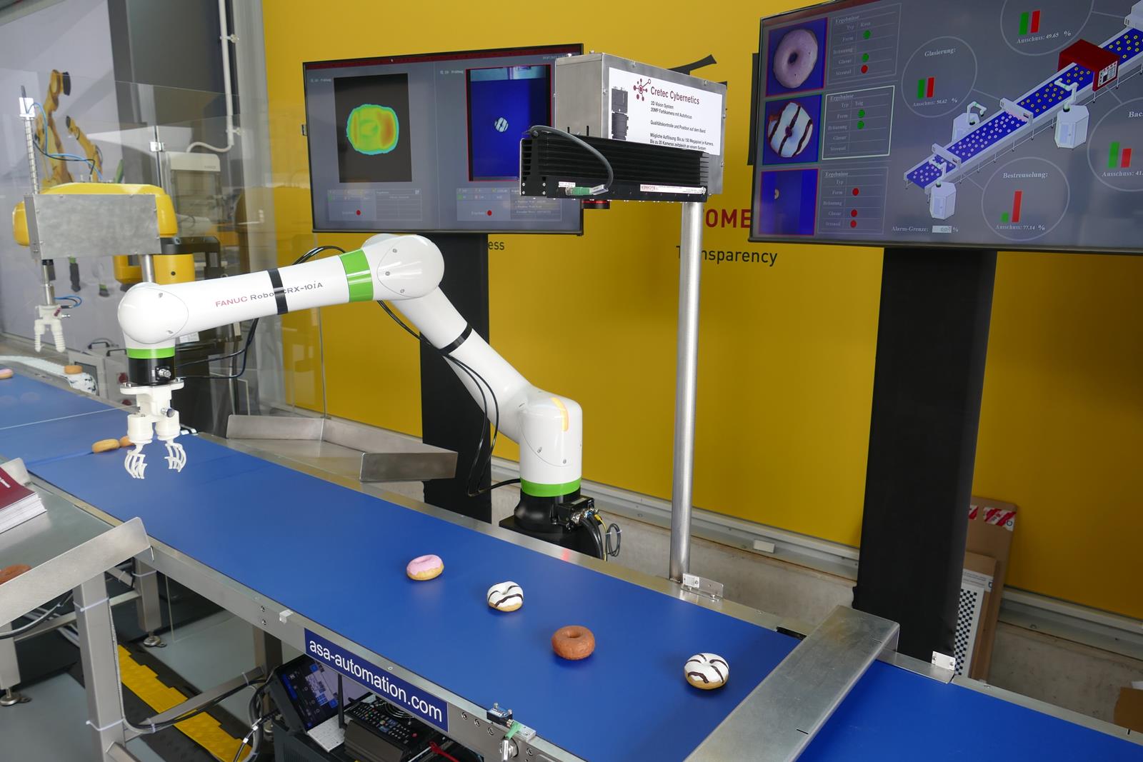 Bilder einer Flächenkamera vom Typ Genie Nano von Teledyne DALSA werden an der zweiten Bildverarbeitungsstation verwendet, um die Farbe, die komplette Form sowie die Toppings der Donuts mit all ihren Variationen von oben zu kontrollieren. Bilder einer Flächenkamera vom Typ Genie Nano von Teledyne DALSA werden an der zweiten Bildverarbeitungsstation verwendet, um die Farbe, die komplette Form sowie die Toppings der Donuts mit all ihren Variationen von oben zu kontrollieren.